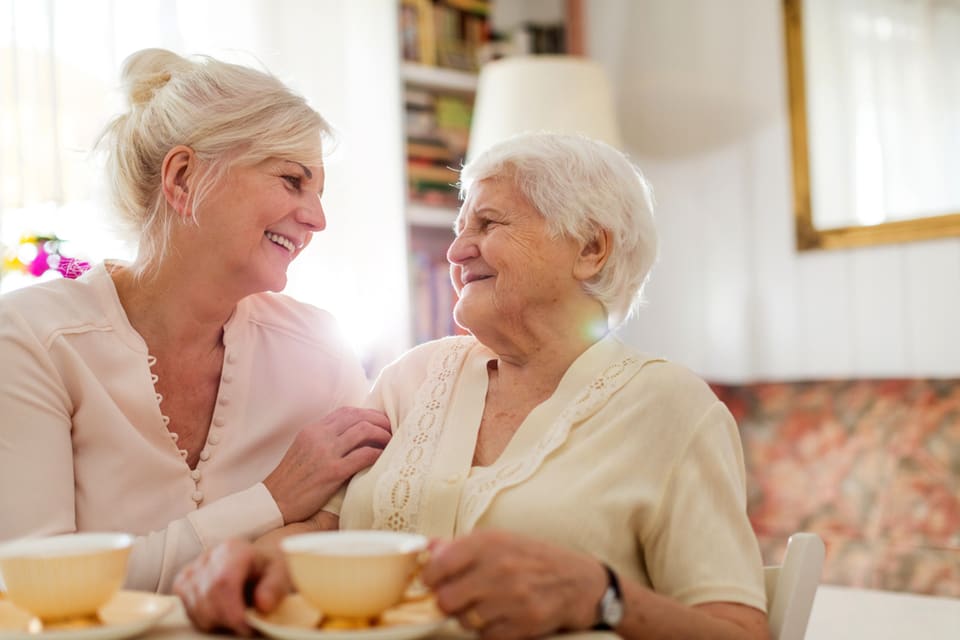 一位老年和中年妇女一边喝着茶一边笑。