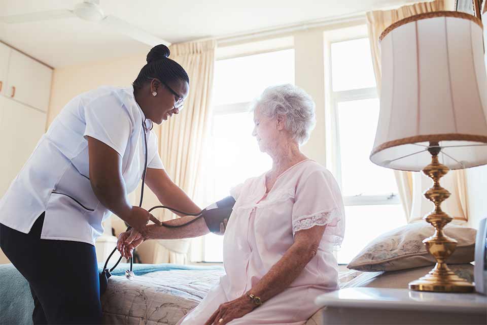 一位老年妇女正在由护工测量她的血压。