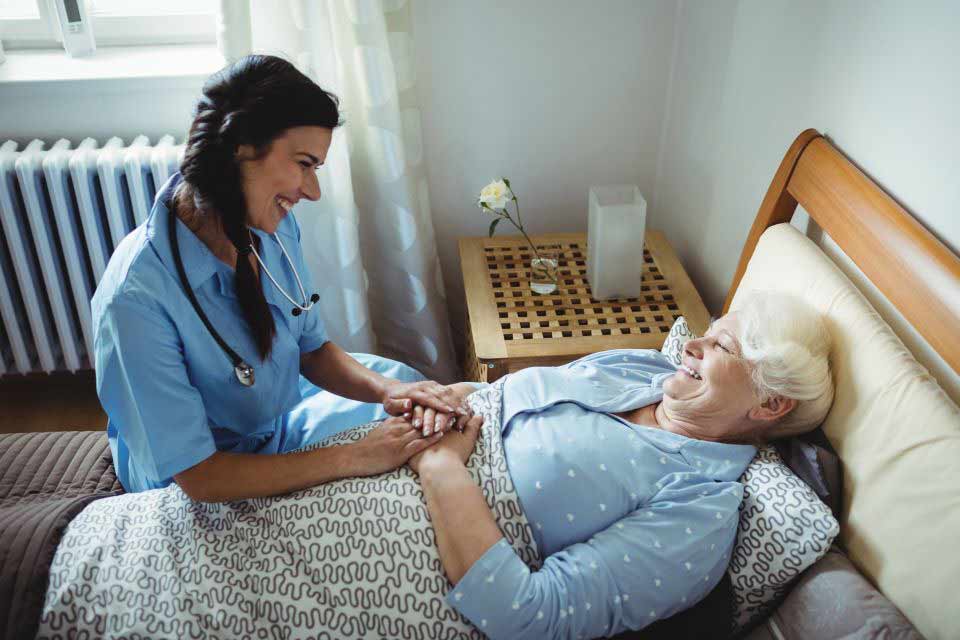 家庭护理提供者照顾卧床的老年妇女。
