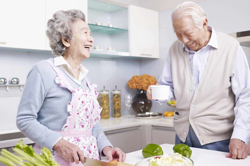 老夫妇笑着切菜做晚餐。