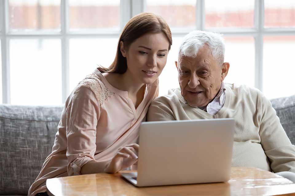 老人和他的女儿旅游高级居住社区在他们的笔记本电脑。